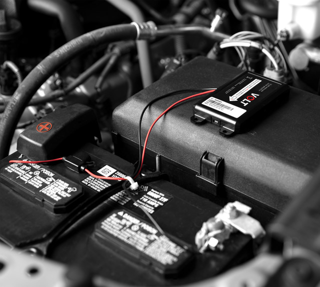 GPS tracker installed on vehicle battery in engine bay